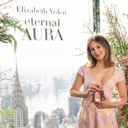 Woman in a floral dress holding a bottle with New York City skyline view including the Chrysler Building in the background