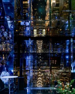 Night view of a midtown event space in NYC with reflective glass walls showcasing city lights and the Chrysler Building.