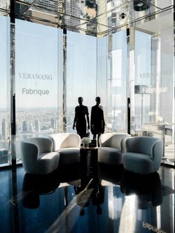 Midtown event space with curved white chairs and mannequins against large glass windows offering a panoramic city view.
