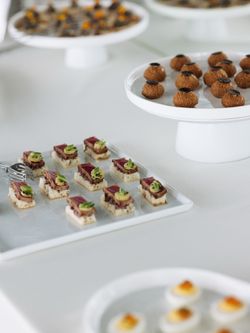 Assorted upscale appetizers displayed on white platters at a private event space.