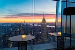 Midtown event space at sunset featuring tables and panoramic view of the Empire State Building and Manhattan skyline.