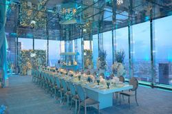 Elegant midtown event space in NYC with panoramic floor-to-ceiling glass windows, decorated for a formal dining event.