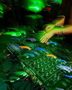 DJ hands adjusting controls on a Pioneer DJ mixer at a Midtown event space with vibrant green lighting effects.