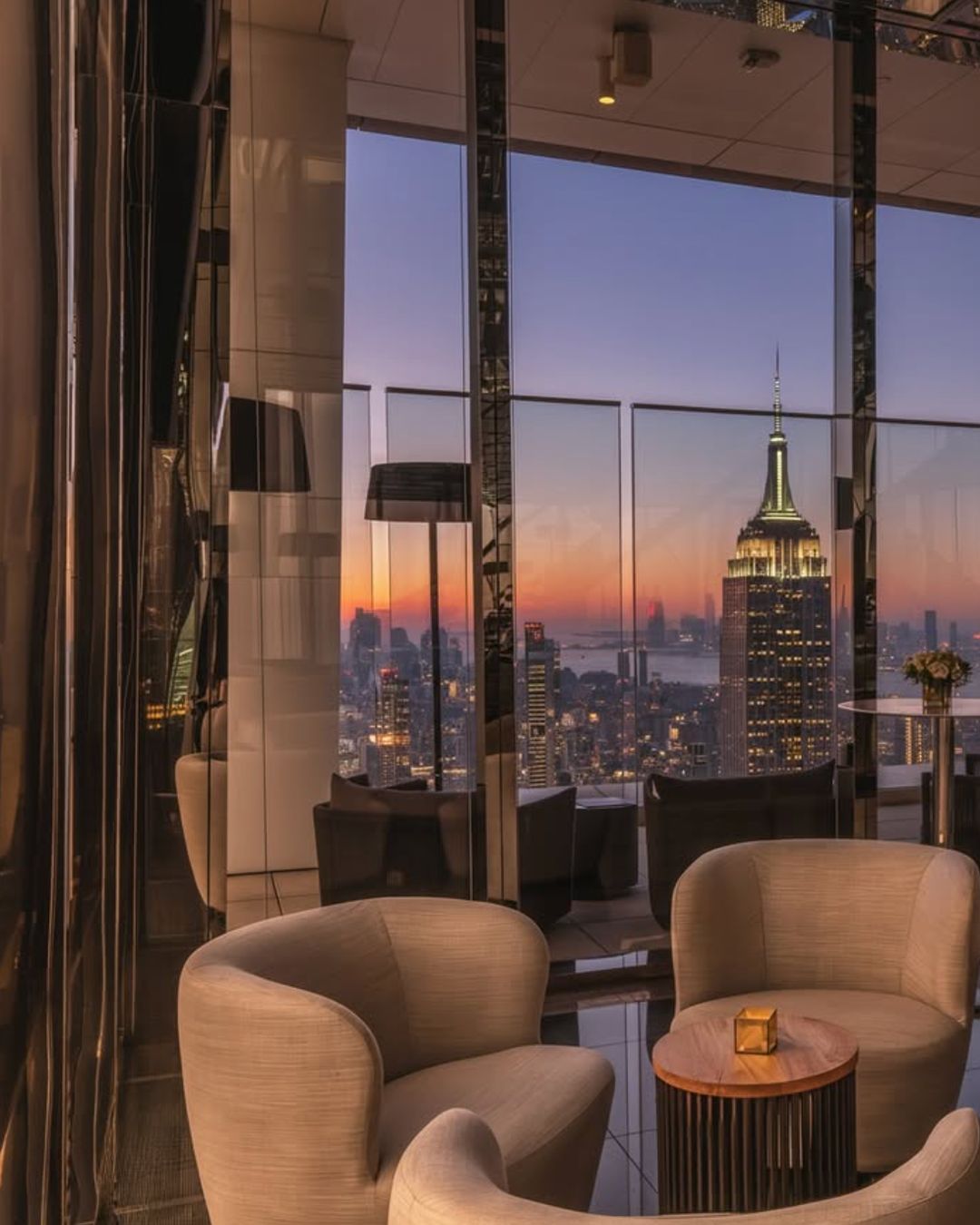 Elegant seating area with stunning views of the NYC skyline, highlighting the Empire State Building at sunset.