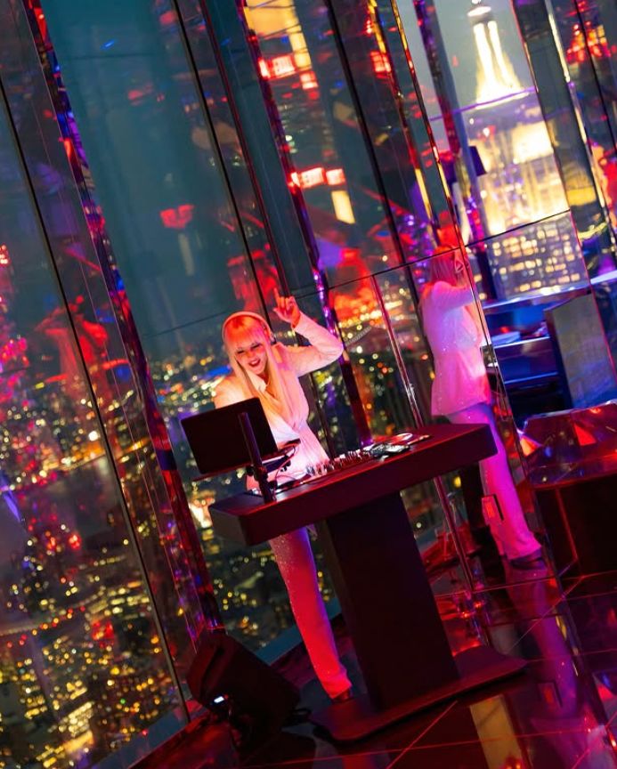 A DJ performs in a vibrant, mirrored event space with stunning NYC views at SUMMIT Events.