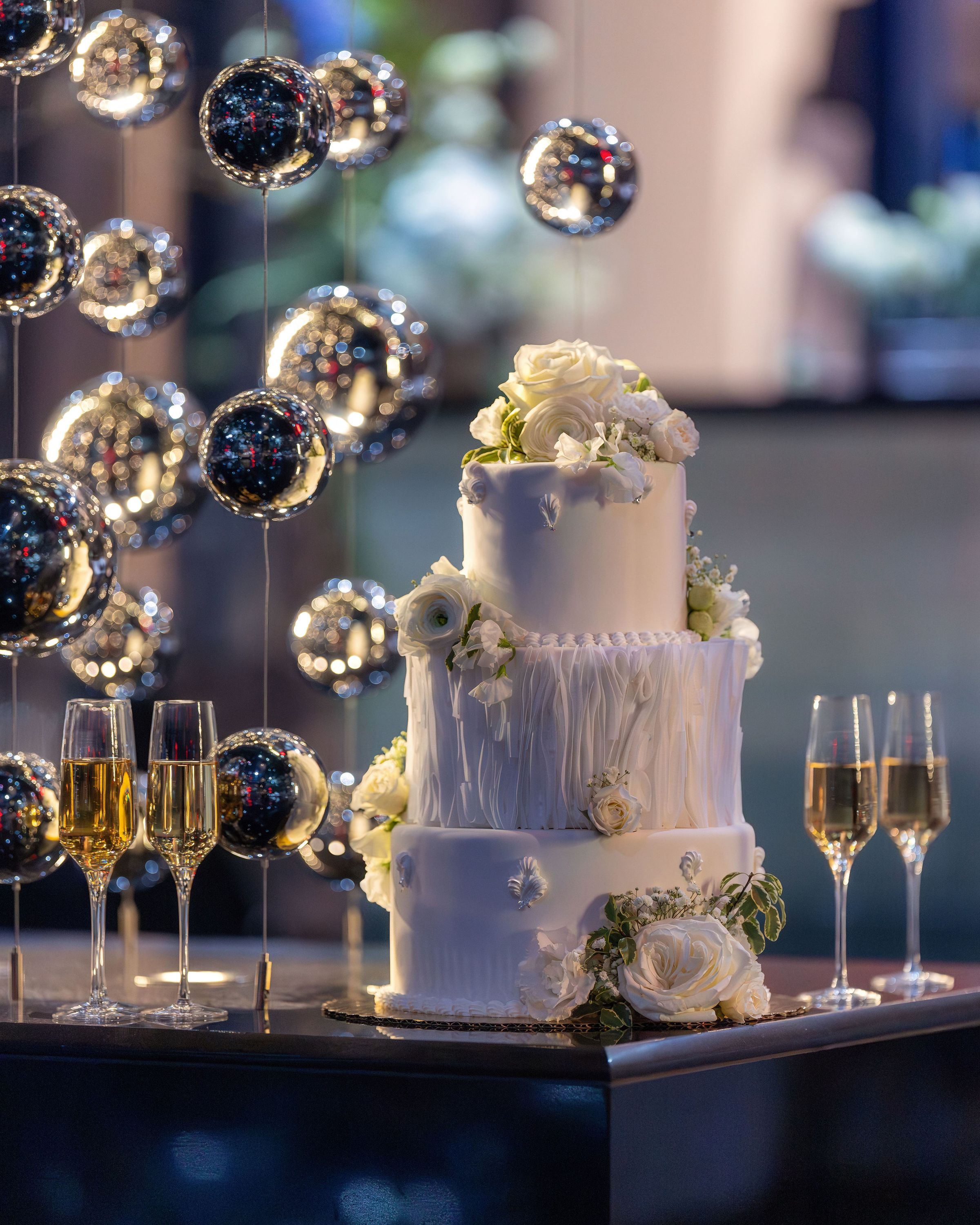 A beautifully designed wedding cake decorated with flowers, complemented by champagne glasses.